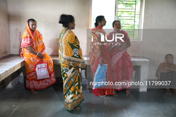 Relatives wait while Tumpa Das, age 29, a woman Dom, cremates a dead body in a furnace inside a crematorium in the Baruipur Panchayat area i...