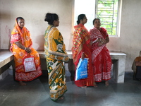 Relatives wait while Tumpa Das, age 29, a woman Dom, cremates a dead body in a furnace inside a crematorium in the Baruipur Panchayat area i...