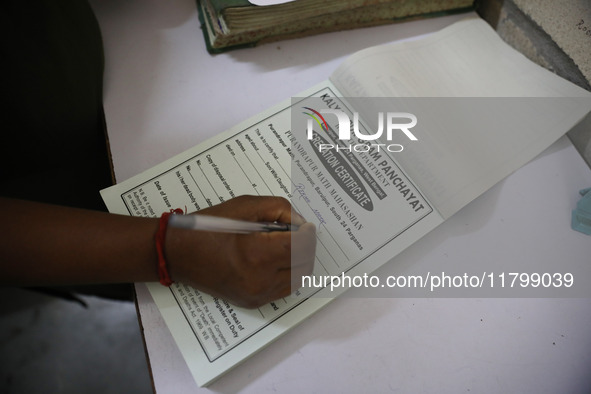 Tumpa Das, age 29, prepares a death certificate while cremating a dead body in a furnace inside a crematorium in the Baruipur Panchayat area...