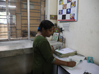 Tumpa Das, age 29, prepares a death certificate while cremating a dead body in a furnace inside a crematorium in the Baruipur Panchayat area...