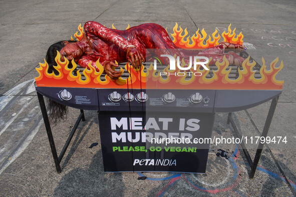 Activists of People for the Ethical Treatment of Animals (PETA) are seen drenched in fake blood and sleep on a figurative oven as they stage...