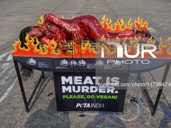 Activists of People for the Ethical Treatment of Animals (PETA) are seen drenched in fake blood and sleep on a figurative oven as they stage...