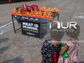 Activists of People for the Ethical Treatment of Animals (PETA) are seen drenched in fake blood and sleep on a figurative oven as they stage...