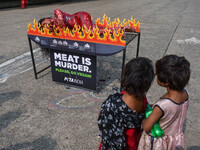 Activists of People for the Ethical Treatment of Animals (PETA) are seen drenched in fake blood and sleep on a figurative oven as they stage...