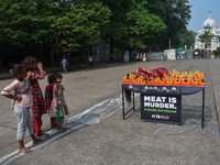 Activists of People for the Ethical Treatment of Animals (PETA) are seen drenched in fake blood and sleep on a figurative oven as they stage...