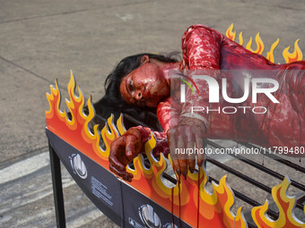 Activists of People for the Ethical Treatment of Animals (PETA) are seen drenched in fake blood and sleep on a figurative oven as they stage...