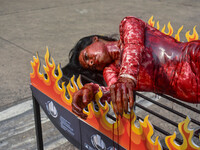 Activists of People for the Ethical Treatment of Animals (PETA) are seen drenched in fake blood and sleep on a figurative oven as they stage...