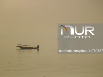 A fisherman smokes hookah in the Dal Lake amid fog in Srinagar, Jammu and Kashmir, on November 22, 2024. (