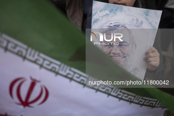 A young Iranian boy holds a portrait of Lebanon's Hezbollah leader, Hassan Nasrallah, who was killed in an Israeli airstrike in a suburb of...