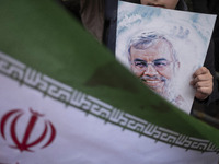 A young Iranian boy holds a portrait of Lebanon's Hezbollah leader, Hassan Nasrallah, who was killed in an Israeli airstrike in a suburb of...