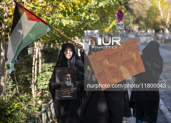 Veiled Iranian women carry a Palestinian flag and a placard while participating in an anti-Israeli rally in front of the United Nations (UN)...