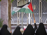 A veiled Iranian woman waves a Palestinian flag while participating in an anti-Israeli rally in front of the United Nations (UN) office in n...