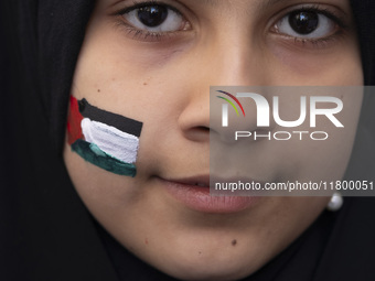 A veiled young Iranian girl with a painted Palestinian flag on her face looks on while participating in an anti-Israeli rally in front of th...