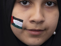 A veiled young Iranian girl with a painted Palestinian flag on her face looks on while participating in an anti-Israeli rally in front of th...