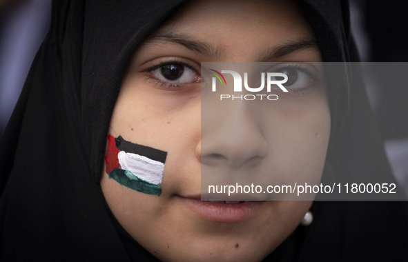 A veiled young Iranian girl with a painted Palestinian flag on her face looks on while participating in an anti-Israeli rally in front of th...