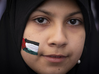 A veiled young Iranian girl with a painted Palestinian flag on her face looks on while participating in an anti-Israeli rally in front of th...