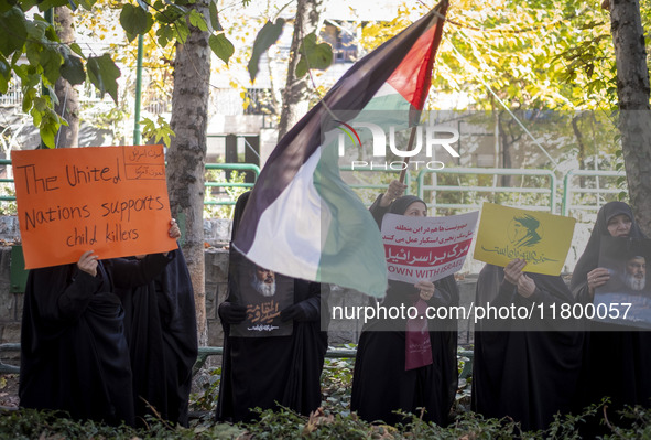 Veiled Iranian women hold portraits of Lebanon's Hezbollah leader, Hassan Nasrallah, a placard, and a Palestinian flag while participating i...