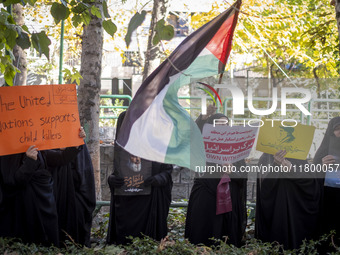 Veiled Iranian women hold portraits of Lebanon's Hezbollah leader, Hassan Nasrallah, a placard, and a Palestinian flag while participating i...