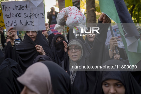 A veiled Iranian woman shouts anti-UN slogans while another woman holds up an anti-UN placard during an anti-Israeli rally in front of the U...