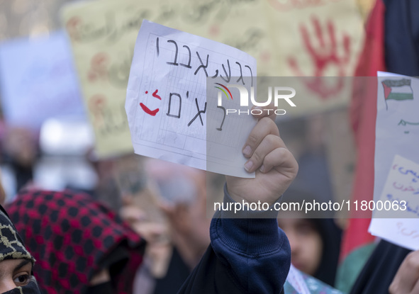 A veiled Iranian woman wearing a Palestinian scarf holds up an anti-Israeli placard that reads, ''Keep waiting, we are coming,'' during an a...