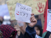 A veiled Iranian woman wearing a Palestinian scarf holds up an anti-Israeli placard that reads, ''Keep waiting, we are coming,'' during an a...