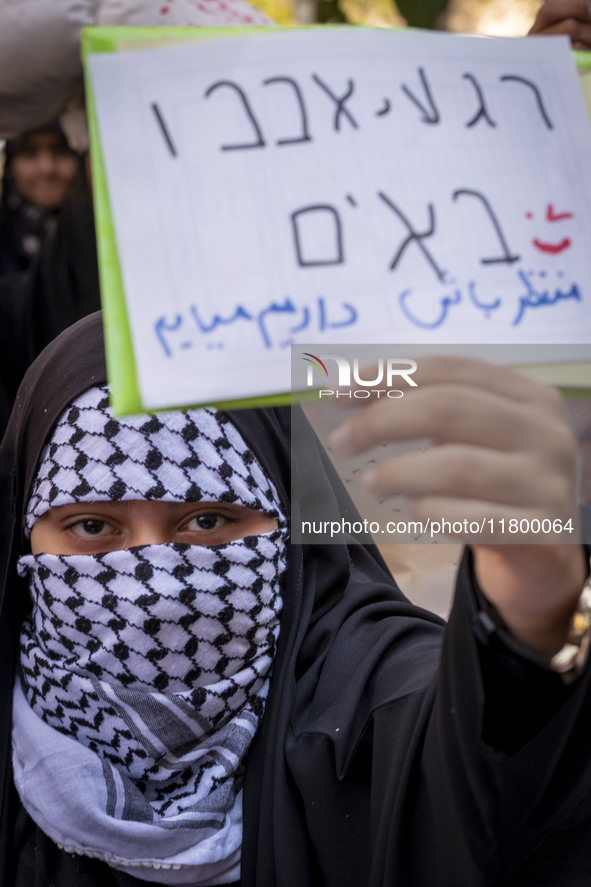 A veiled Iranian woman wearing a Palestinian scarf holds up an anti-Israeli placard that reads, ''Keep waiting, we are coming,'' during an a...