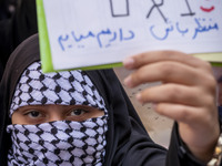 A veiled Iranian woman wearing a Palestinian scarf holds up an anti-Israeli placard that reads, ''Keep waiting, we are coming,'' during an a...