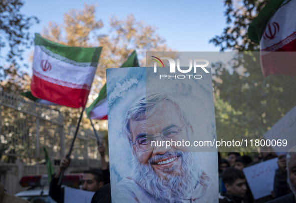 Iranian protesters wave Iranian flags and hold up a portrait of Lebanon's Hezbollah late leader, Hassan Nasrallah, who was killed in an Isra...