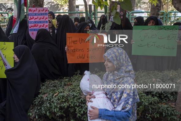 Veiled Iranian women hold an anti-UN and anti-U.S. placard, while a young girl carries a package wrapped in a shroud, symbolizing the body o...