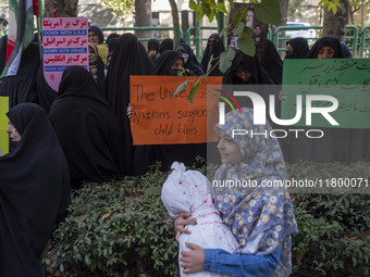 Veiled Iranian women hold an anti-UN and anti-U.S. placard, while a young girl carries a package wrapped in a shroud, symbolizing the body o...