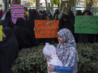 Veiled Iranian women hold an anti-UN and anti-U.S. placard, while a young girl carries a package wrapped in a shroud, symbolizing the body o...