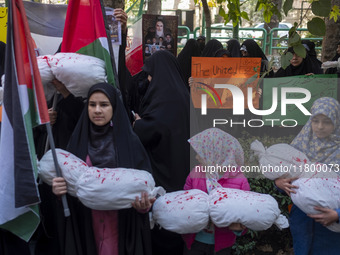 A veiled Iranian woman holds an anti-UN placard, while young girls hold packages wrapped in shrouds, symbolizing the bodies of Palestinian a...