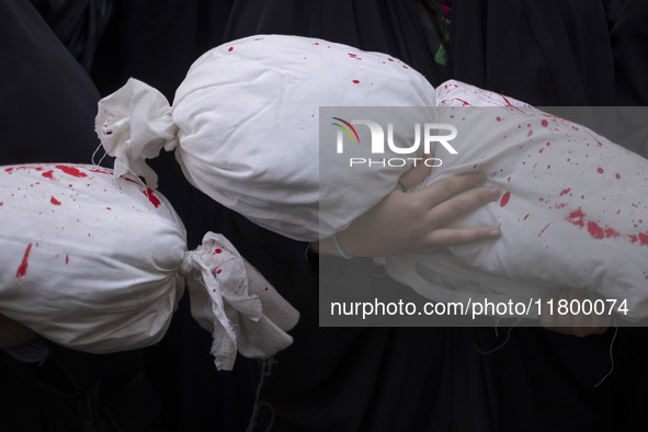 A veiled young Iranian girl holds a package wrapped in a shroud, symbolizing the body of a Palestinian child, during an anti-Israeli rally i...