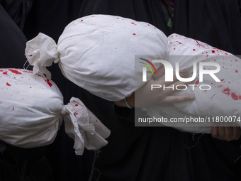 A veiled young Iranian girl holds a package wrapped in a shroud, symbolizing the body of a Palestinian child, during an anti-Israeli rally i...