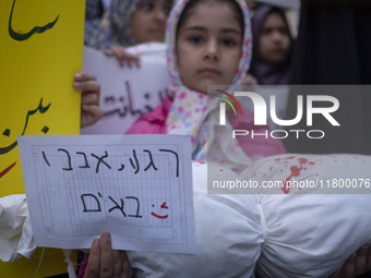 A young veiled girl holds an anti-Israeli placard that reads, ''Keep waiting, we are coming,'' and a package wrapped in a shroud, symbolizin...