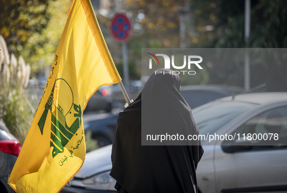 A veiled Iranian woman carries a flag of Lebanon's Hezbollah while walking along a street after participating in an anti-Israeli rally in fr...