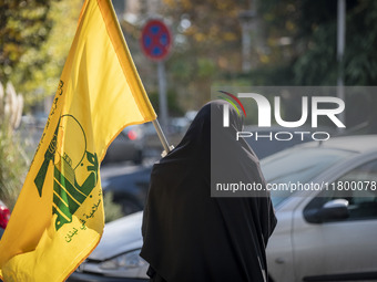 A veiled Iranian woman carries a flag of Lebanon's Hezbollah while walking along a street after participating in an anti-Israeli rally in fr...