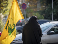 A veiled Iranian woman carries a flag of Lebanon's Hezbollah while walking along a street after participating in an anti-Israeli rally in fr...