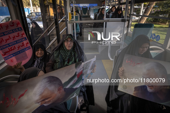 Veiled Iranian women hold an anti-U.S., anti-British, and anti-Israeli placard, along with portraits of the former commander of the Islamic...