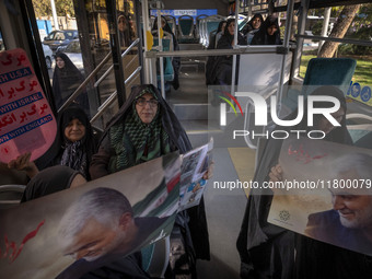 Veiled Iranian women hold an anti-U.S., anti-British, and anti-Israeli placard, along with portraits of the former commander of the Islamic...