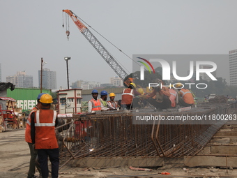 Labourers work at a metro railway station construction site in Kolkata, India, on November 22, 2024. (