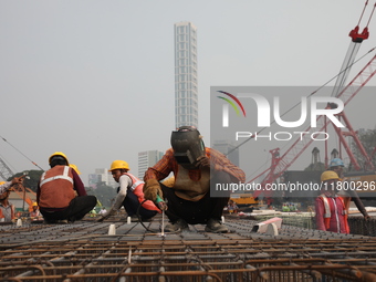 Labourers work at a metro railway station construction site in Kolkata, India, on November 22, 2024. (