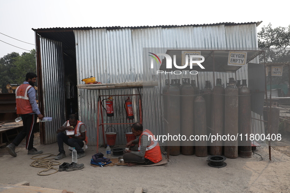 Labourers eat their food at a metro railway station construction site in Kolkata, India, on November 22, 2024. 