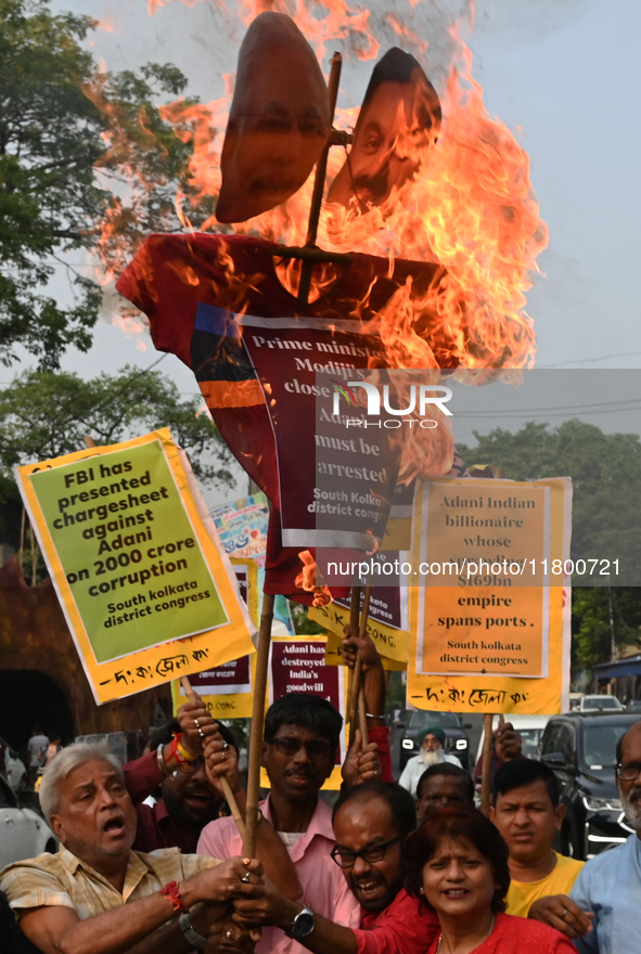 Congress party workers hold placards and burn an effigy during a protest demanding the arrest of Adani Group chairman Gautam Adani over alle...