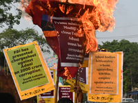 Congress party workers hold placards and burn an effigy during a protest demanding the arrest of Adani Group chairman Gautam Adani over alle...