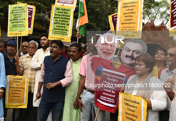 Congress party workers hold placards and burn an effigy during a protest demanding the arrest of Adani Group chairman Gautam Adani over alle...