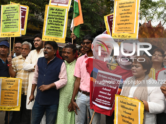 Congress party workers hold placards and burn an effigy during a protest demanding the arrest of Adani Group chairman Gautam Adani over alle...