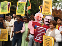 Congress party workers hold placards and burn an effigy during a protest demanding the arrest of Adani Group chairman Gautam Adani over alle...