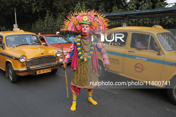 Indian tribal Chaw artists from Purulia stand in front of a Yellow Ambassador Taxi during the West Bengal Government-hosted ''Jangalmahal Ut...