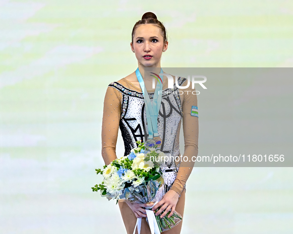 Bronze medalist Takhmina Ikromova of Uzbekistan celebrates on the podium after the Individual Ball Final of the International Rhythmic Gymna...